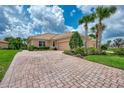 Home with paver driveway, two-car garage, and tropical landscaping at 13104 Creekside Ln, Port Charlotte, FL 33953