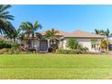 Beautiful home featuring a lush green lawn, well-maintained landscaping, and tropical palm trees at 65 Par View Ter, Rotonda West, FL 33947