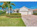 Well-maintained house with a three-car garage, palm trees, and manicured lawn at 13025 Cedar Creek Dr, Port Charlotte, FL 33953