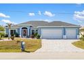 House exterior featuring a three-car garage and landscaped yard at 13838 Begonia Cir, Port Charlotte, FL 33981