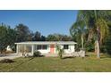 Ranch-style home with a coral door, green trim, and a spacious lawn at 1446 Fairless Rd, Englewood, FL 34223