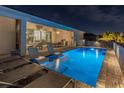 Night view of an inviting backyard pool with sun loungers, outdoor kitchen and seating area at 8198 Clyde Cir, Port Charlotte, FL 33981