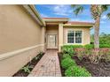 Front entrance with brick walkway, landscaping, and light beige walls at 13241 Creekside Ln, Port Charlotte, FL 33953