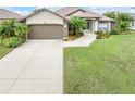 House exterior showcasing a two-car garage and well-manicured lawn at 171 Medalist Rd, Rotonda West, FL 33947