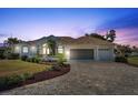 Beautiful two-story home with a three-car garage and a brick driveway at dusk at 385 Pelican Bnd, Placida, FL 33946