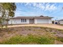 White single-story home with a brown roof, a gravel driveway, and a spacious yard at 560 Sandlor Dr, Englewood, FL 34223