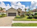 Tan house with brown garage door, blue front door, and landscaped yard at 26812 Pavin Dr, Englewood, FL 34223