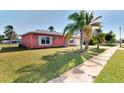 Side view of a pink house with palm trees and a grassy yard at 3460 Lullaby Rd, North Port, FL 34287