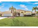 House exterior showcasing a yellow painted home with palm trees and a lush lawn at 738 Boundary Blvd, Rotonda West, FL 33947