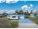 Single-story home with light blue exterior, metal roof, and spacious driveway at 850 E 2Nd St, Englewood, FL 34223