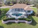 Aerial view of a screened-in pool and spa with surrounding landscaping at 110 Barracuda Dr, Placida, FL 33946