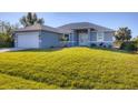 Newly built home with gray siding, a large grassy yard, and a two-car garage at 119 White Pine Dr, Rotonda West, FL 33947