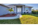 Modern front entry with double doors, landscaping, and a walkway at 119 White Pine Dr, Rotonda West, FL 33947