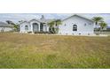 Single-story home with light gray exterior, palm trees, and manicured lawn at 142 Broadmoor Ln, Rotonda West, FL 33947