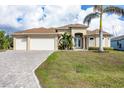 Tan house with three-car garage, palm trees, and landscaped lawn at 17164 Canary Ln, Port Charlotte, FL 33948