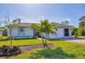 One-story home with attached garage,palm trees, and landscaped lawn at 185 Cougar Way, Rotonda West, FL 33947