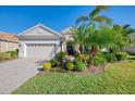 House with a beige facade, two-car garage, and lush landscaping at 21228 Sandal Foot Dr, Venice, FL 34293