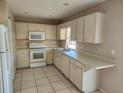 Galley style kitchen with white cabinets and appliances at 7330 Regina Dr, Englewood, FL 34224