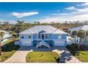 Two-story light blue house with white trim, metal roof, and a paved driveway at 9240 Pine Cove Dr, Englewood, FL 34224