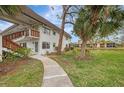 Condo building with walkway leading to the entrance, surrounded by lush landscaping at 1 Quails Run Blvd # 5, Englewood, FL 34223