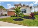 Front yard view of a tan house with landscaping and paver driveway at 305 Daylily Blvd, Nokomis, FL 34275