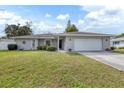 Single-story house with a gray exterior, attached garage, and well-maintained lawn at 1035 Oleander St, Englewood, FL 34223