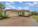 Attached garage with a tan exterior matching the house and a brick paved driveway at 13048 Creekside Ln, Port Charlotte, FL 33953