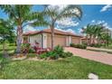 Exterior view of a villa with a tan garage door, landscaping and palm trees at 24028 Canterwood Way, Venice, FL 34293