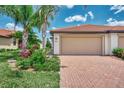 Exterior view of a villa with a tan garage door and brick pavers at 24028 Canterwood Way, Venice, FL 34293