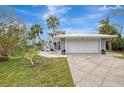 A gray house with a white garage door and palm trees in the front at 900 Oxford Dr, Englewood, FL 34223