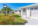 Front entryway with a screened porch, lush landscaping, and a decorative gate at 958 Osceola Blvd, Englewood, FL 34223