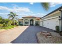 Home exterior with a three-car garage, brick driveway, and well-maintained landscaping at 10705 Tarflower Dr, Venice, FL 34293