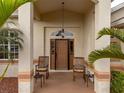 Front door entry with rocking chairs and a covered porch at 185 Rotonda E Blvd, Rotonda West, FL 33947