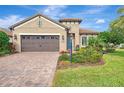 Tan house with brown garage door, landscaping, and palm trees at 26906 Weiskopf Dr, Englewood, FL 34223