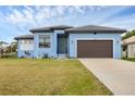 Newly built light blue house with a brown garage door and well-manicured lawn at 4220 Cape Haze Dr, Placida, FL 33946