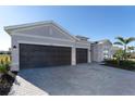 Two-car garage with dark brown doors and paver driveway at 8565 Saint Kitts Cir, Englewood, FL 34224