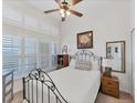 Bright bedroom with iron bed frame, window shutters and ceiling fan at 102 Natures Way # 2305, Rotonda West, FL 33947