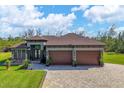 House exterior boasts a three-car garage, paver driveway, and lush landscaping at 10451 Hatchett Cir, Port Charlotte, FL 33981