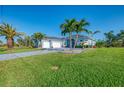 Light blue home with a three-car garage, paver driveway, and lush green lawn at 1061 Boundary Blvd, Rotonda West, FL 33947