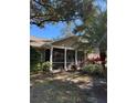 Tan one-story house with covered porch, lush landscaping, and mature trees at 1415 Winding Oak Dr, Port Charlotte, FL 33948