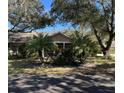 Tan one-story house with covered porch, palm trees, and lush landscaping at 1415 Winding Oak Dr, Port Charlotte, FL 33948