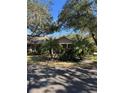 Tan one-story house with covered porch, palm trees, and lush landscaping at 1415 Winding Oak Dr, Port Charlotte, FL 33948