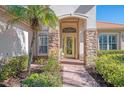 Front entry with stone accents, arched entryway, and yellow door at 2619 Myakka Marsh Ln, Port Charlotte, FL 33953