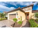 Tan house with stone accents, a two-car garage, and nicely landscaped grounds at 26744 Weiskopf Dr, Englewood, FL 34223