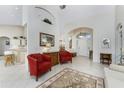 Spacious living room with tiled floors, two red armchairs, and a view of the kitchen at 276 Long Meadow Ln, Rotonda West, FL 33947