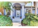 Elegant front entryway with a covered porch, decorative glass door, and lush green landscaping at 52 Marker Rd, Rotonda West, FL 33947