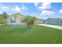 Landscaped yard with palm trees and a light yellow house at 6176 Catalan St, Englewood, FL 34224