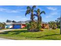 View of coral house with blue garage door and landscaped yard at 62 Marker Rd, Rotonda West, FL 33947