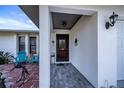 Covered entryway with a dark-red door, teal chairs, and a stone tile floor at 7336 Brookhaven Ter, Englewood, FL 34224