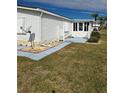 Side view of a white manufactured home with a walkway and small patio at 8479 Tanaka Dr, Englewood, FL 34224